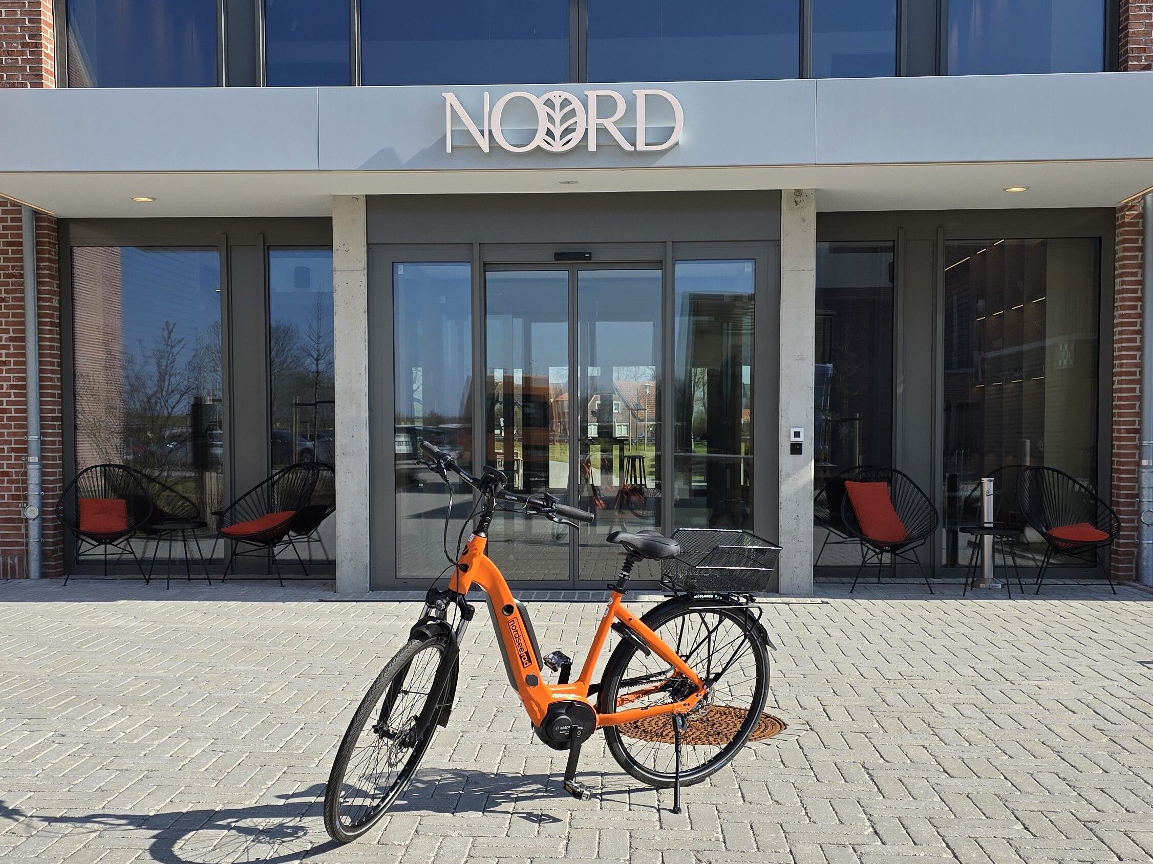 Fahrradverleih: NordseeRad Partnerstation Hotel Noord in Carolinensiel. Fahrrad steht vor Hoteleingang